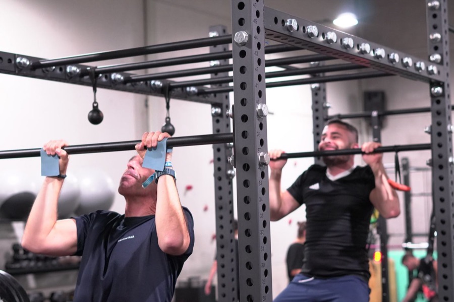 Dos alumnos haciendo dominadas juntos en el rack